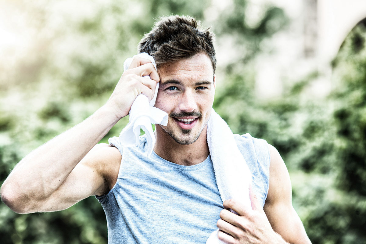 Junger sportlicher Mann mit Handtuch beim Lauftraining