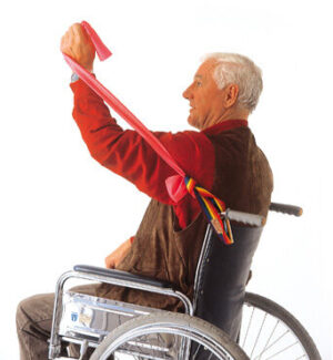 Mann im Rollstuhl trainiert mit Flexaband und Griffschlaufe, die am Rollstuhl befestigt ist